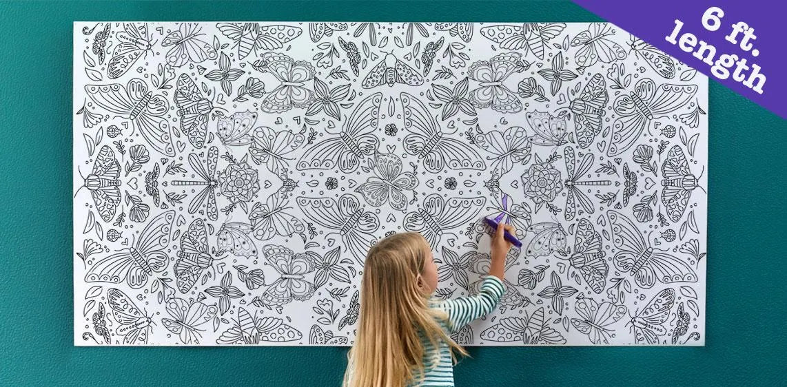 Child coloring a large coloring poster with butterfly and flower pattern  on a teal wall.